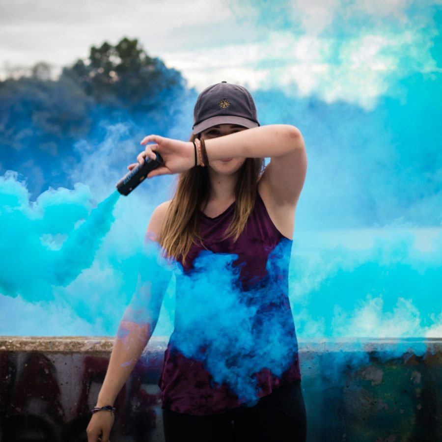 pexels-photo-445109-445109 A stylish woman surrounded by bright blue smoke outdoors, creating a dynamic fashion statement.